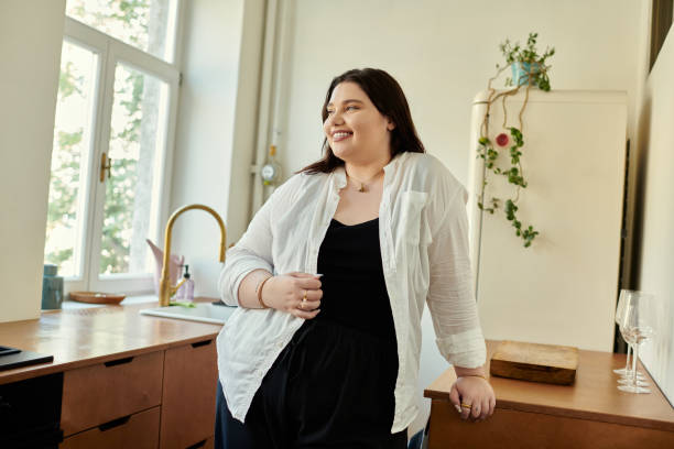 A plus size woman enjoys her time at home in a stylish kitchen.