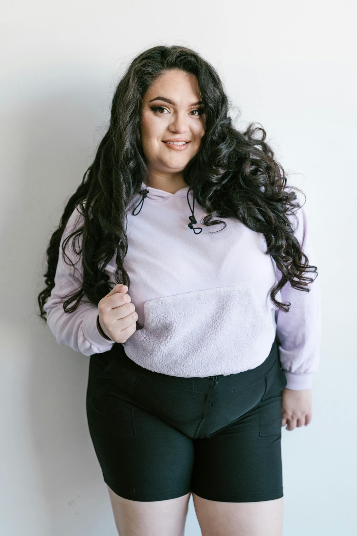 Portrait of a confident plus-size woman with curly hair, wearing casual fashion with a joyful expression.