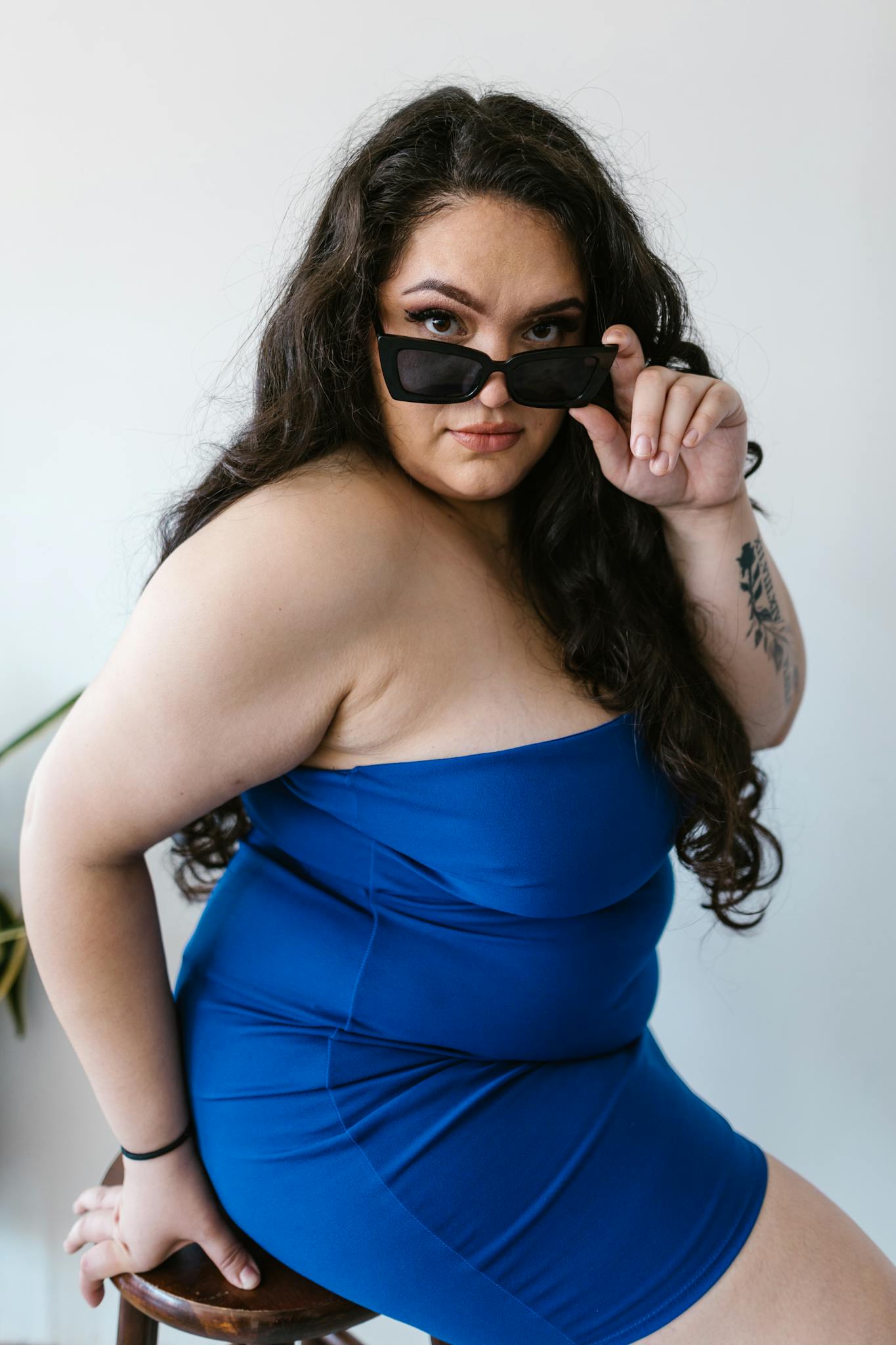 Stylish plus size model in a blue dress and sunglasses, embracing confidence and body positivity.